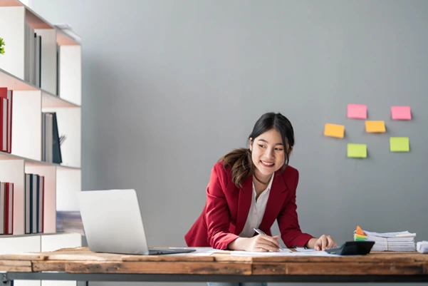happy woman smiling as she works at her tidy, feng shui-optimized office desk happy woman smiling as she works at her tidy, feng shui-optimized office desk