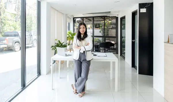 A businesswoman stands confidently in a bright, modern office with large windows, demonstrating good feng shui with natural light A businesswoman stands confidently in a bright, modern office with large windows, demonstrating good feng shui with natural light