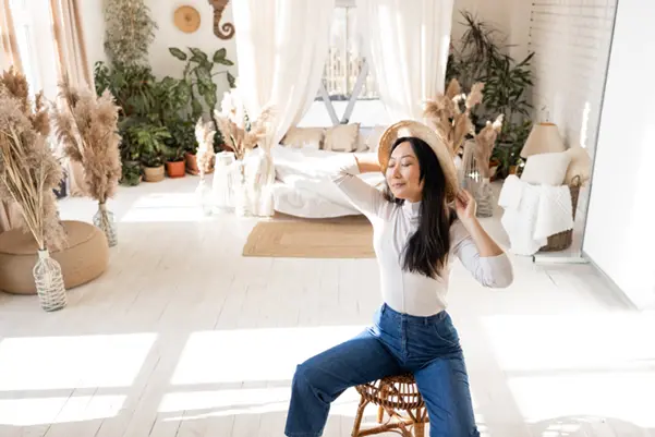 A professional feng shui consultant helps create a balanced, harmonious room A woman sitting on a chair in a light-filled bedroom with various plants
