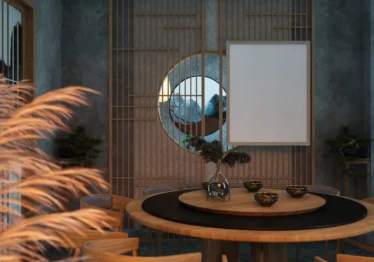 A stylish circular mirror mounted on a wall reflecting a dining table setup.