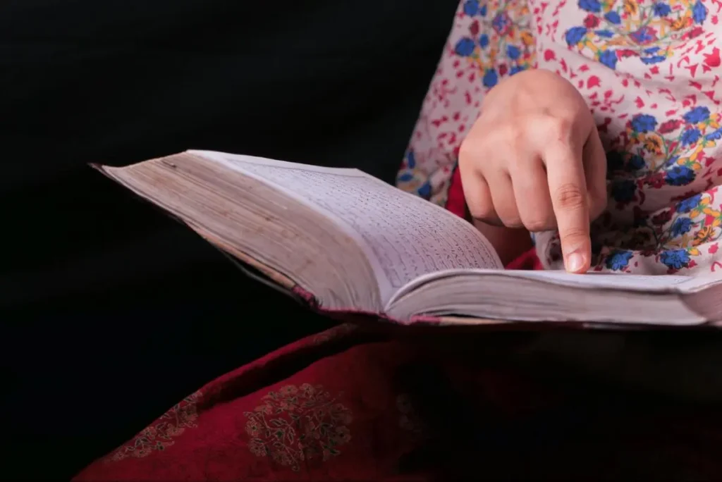 Person pointing to a page in a large reference book representing the detailed analysis process of a Bazi destiny reading