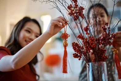 Woman arranging a red feng shui knot on a branch display during a home consultation