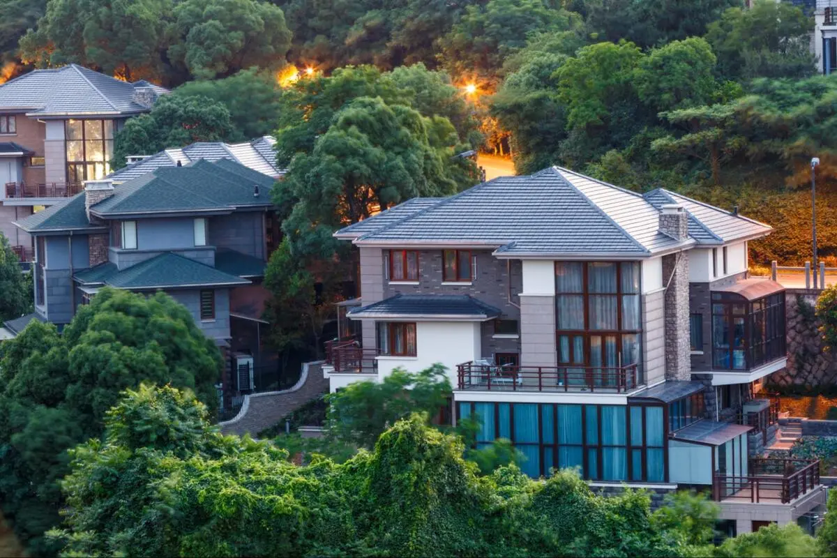 Homes on sloped land surrounded by greenery Houses set among lush greenery on sloped land at dusk