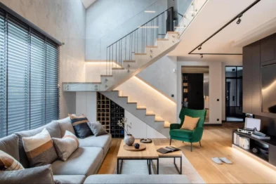 Open-plan living room with a staircase, grey sofa and green armchair in a renovated Singapore home